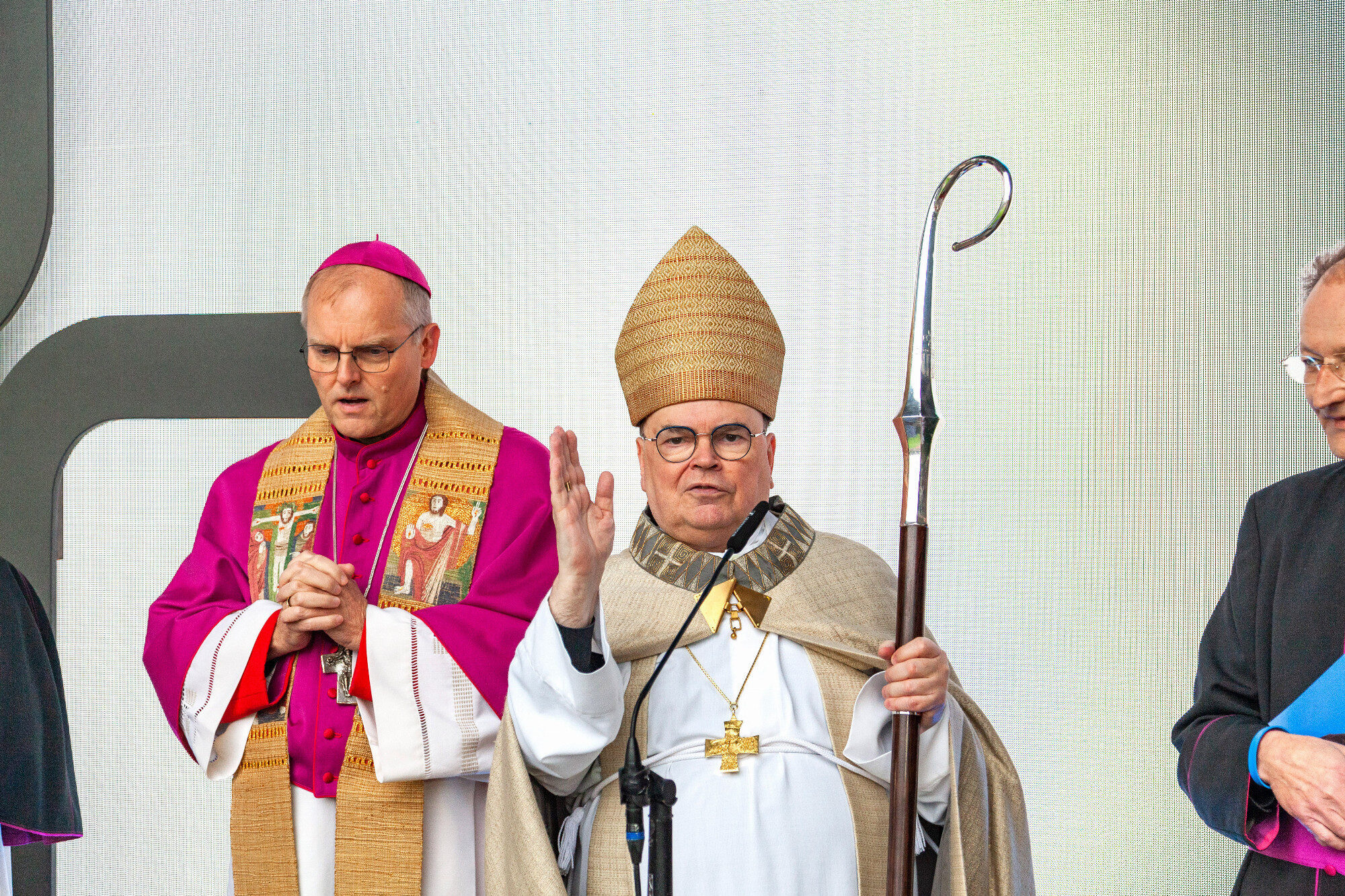Bischof Bertram Meier segnet am Mikrofon mit Stab, WWK Arena Augsburg / Schulwerk