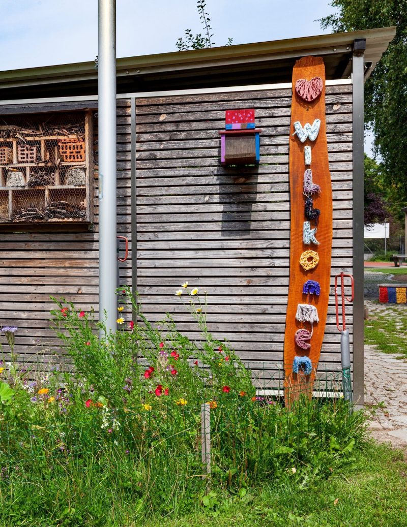 Holzschild mit dem Wort Willkommen und Insektenhotel auf dem Schulgelände der St.-Michael-Grundschule Neu-Ulm