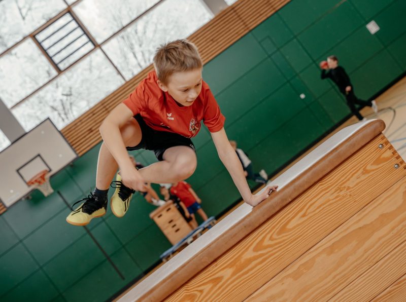 Schüler springt in der Turnhalle über einen Kasten, St.-Michael-Grundschule Neu-Ulm